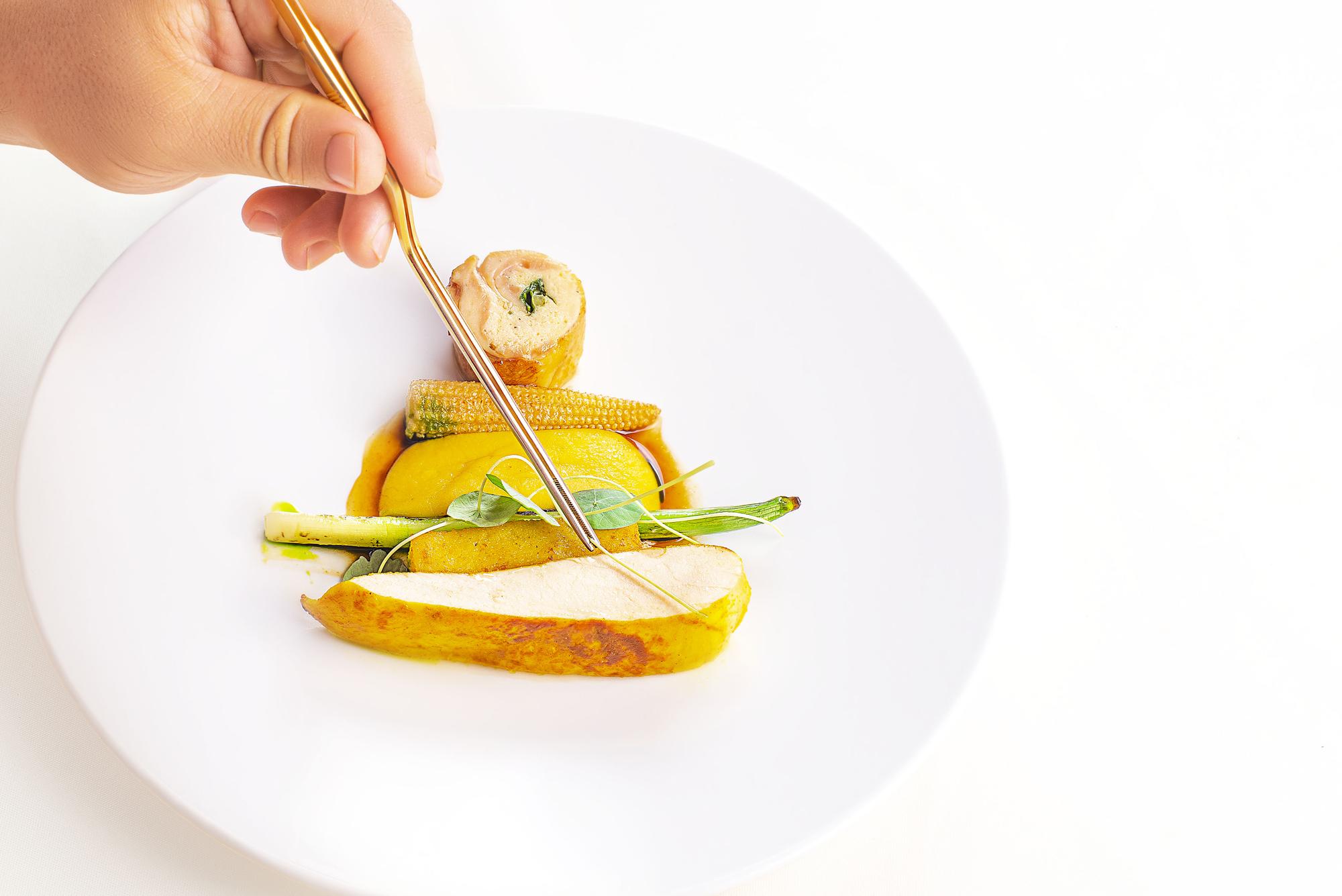 Hands arranging garnish on a plated dish